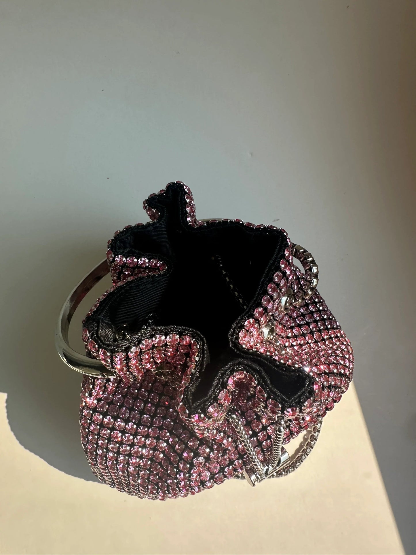 Pink rhinestone bucket bag open to show black fabric lining