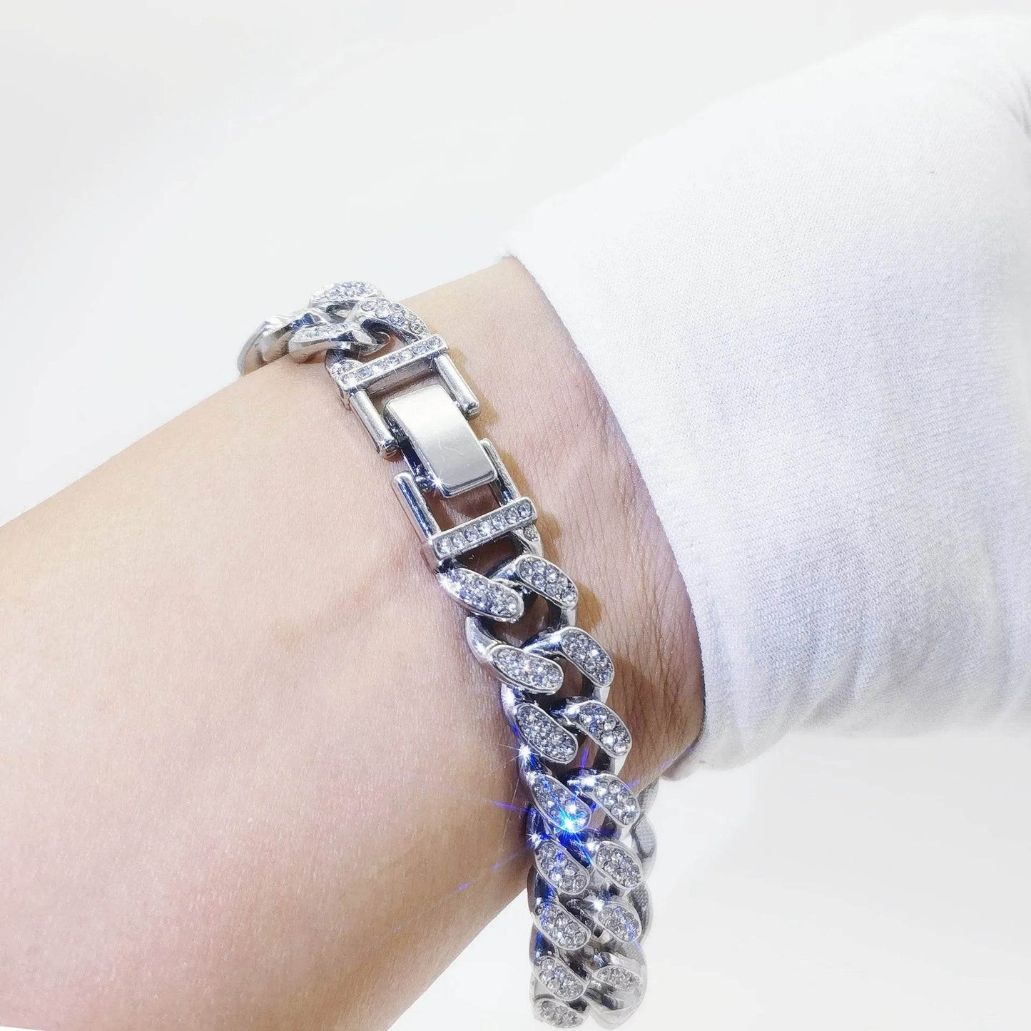 Silver diamond Cuban link bracelet with rectangular clasp on wrist.