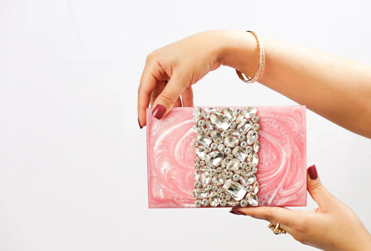 Pink rhinestone embellished clutch bag with decorative gem front