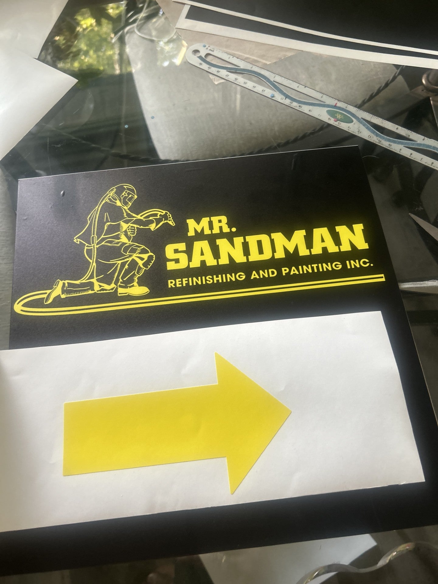 Black custom sign with yellow Mr. Sandman logo and yellow arrow on white backing