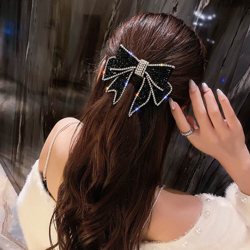 Black rhinestone bow hair clip barrette with silver center, clipped on hair