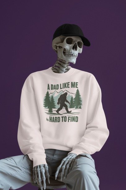 Skeleton wearing a cream A Dad Like Me Is Hard to Find graphic sweatshirt with a Bigfoot forest design