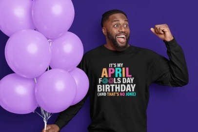 Black birthday graphic tee with April 1 slogan and colorful text, held up