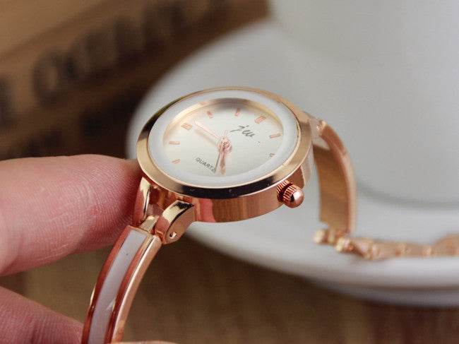 Rose gold watch bracelet close-up with white dial, small markers, and chain-style band