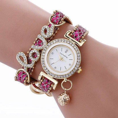 Rhinestone bracelet watch with round white dial, gold-tone bezel, and pink gem strap links