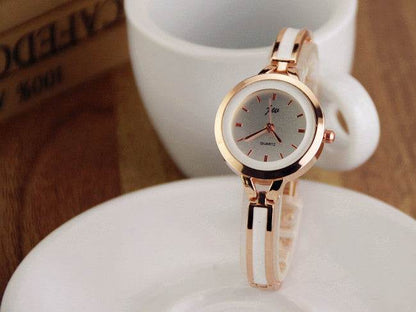 Rose gold watch bracelet with round white dial and clear link band on display pillow