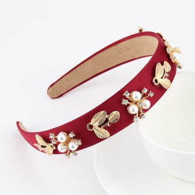 Red satin headband with gold-tone bows, pearls, and small rhinestone flower details
