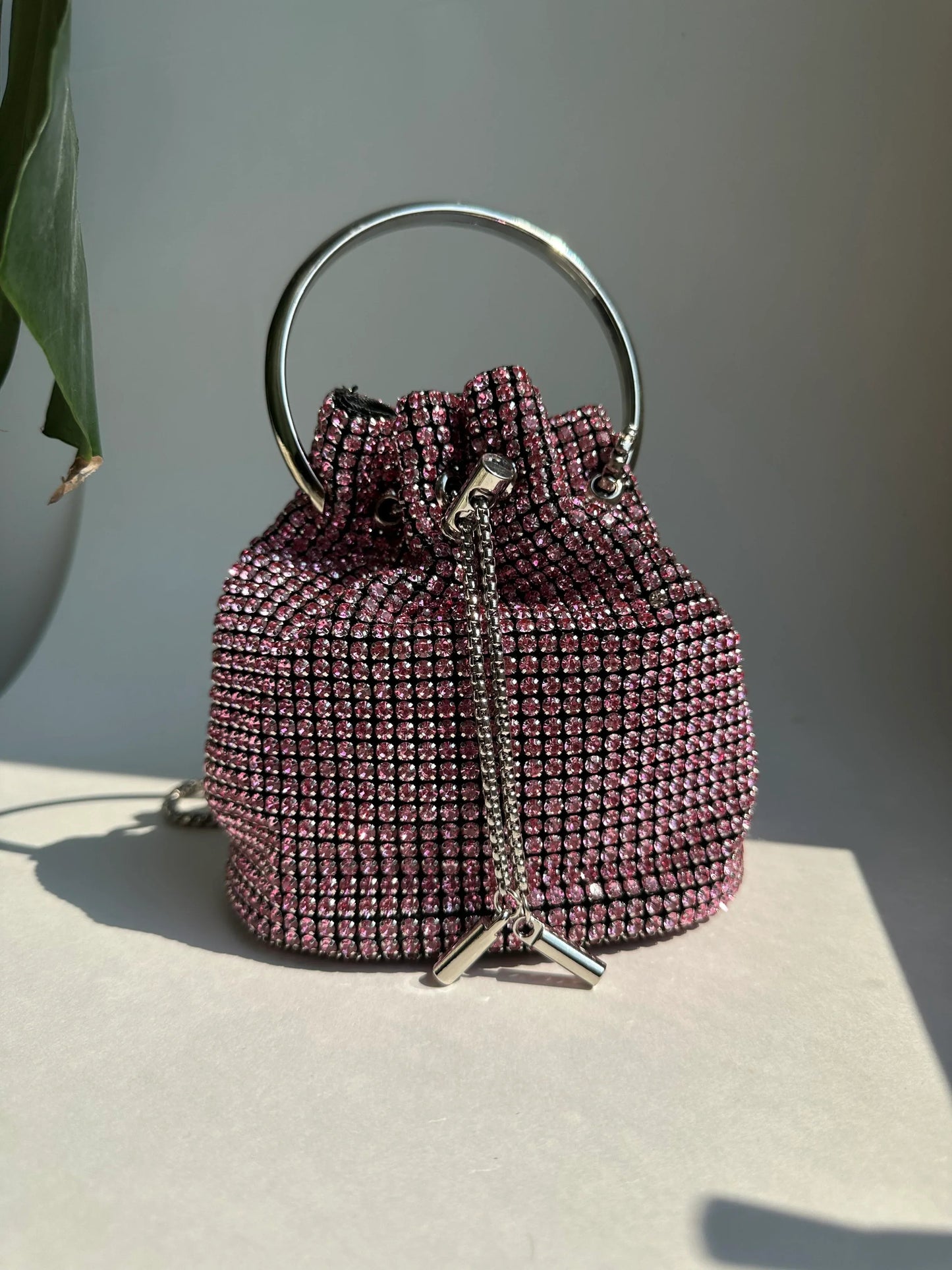 Pink rhinestone bucket bag with drawstring closure and silver top handle
