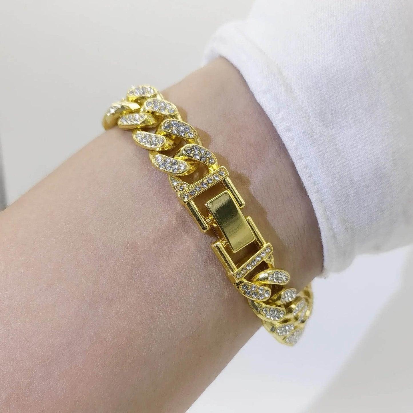 Gold diamond Cuban link bracelet with rectangular clasp on wrist.