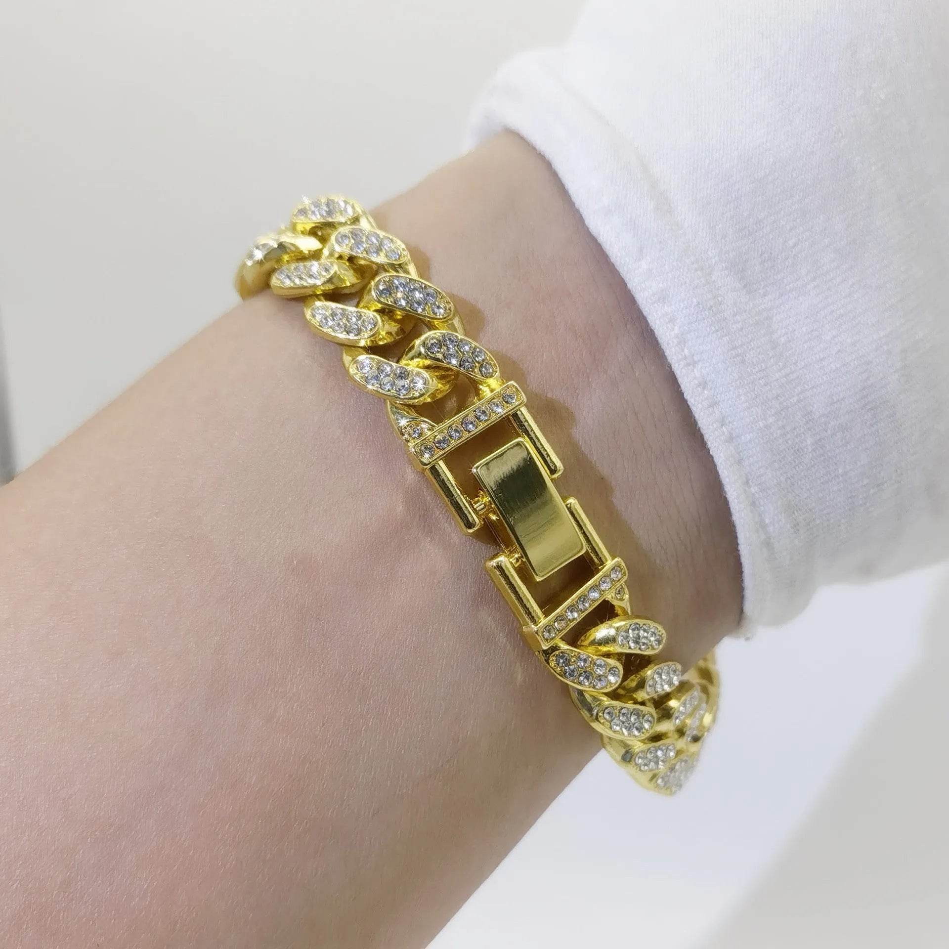 Gold diamond Cuban link bracelet with rectangular clasp on wrist.