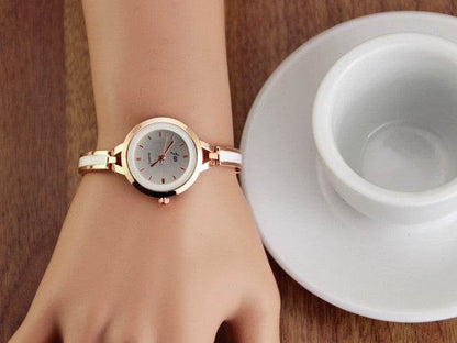 Gold watch bracelet on wrist with round white dial and linked metal band