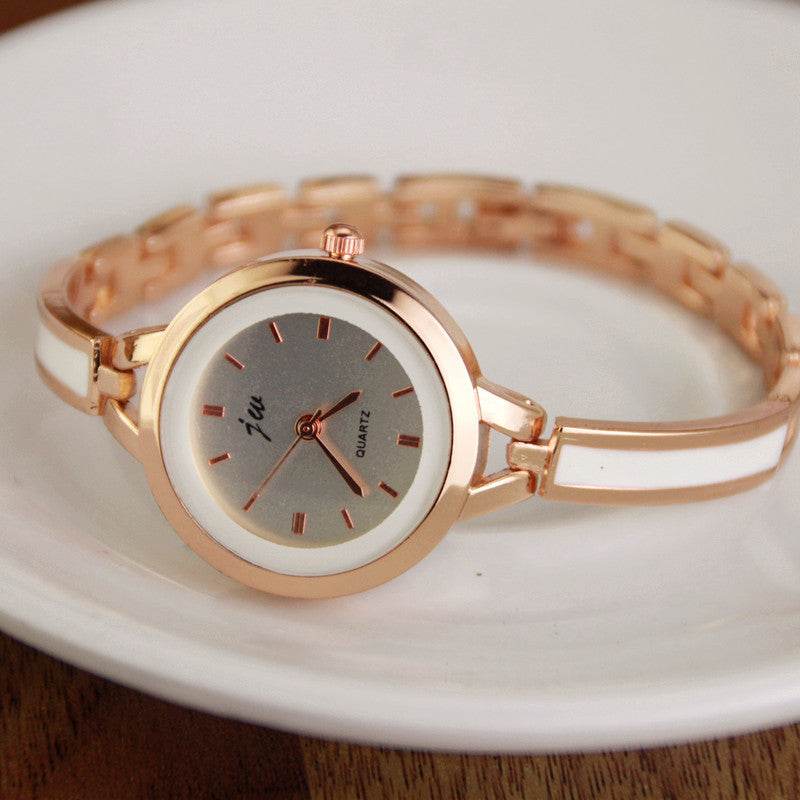 Rose gold watch bracelet with round white dial, red markers, and linked band clasp