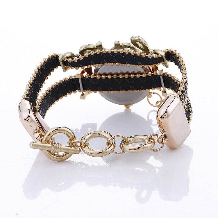 Gold-tone chain bracelet with rhinestone and stud accents, watch hardware partially visible