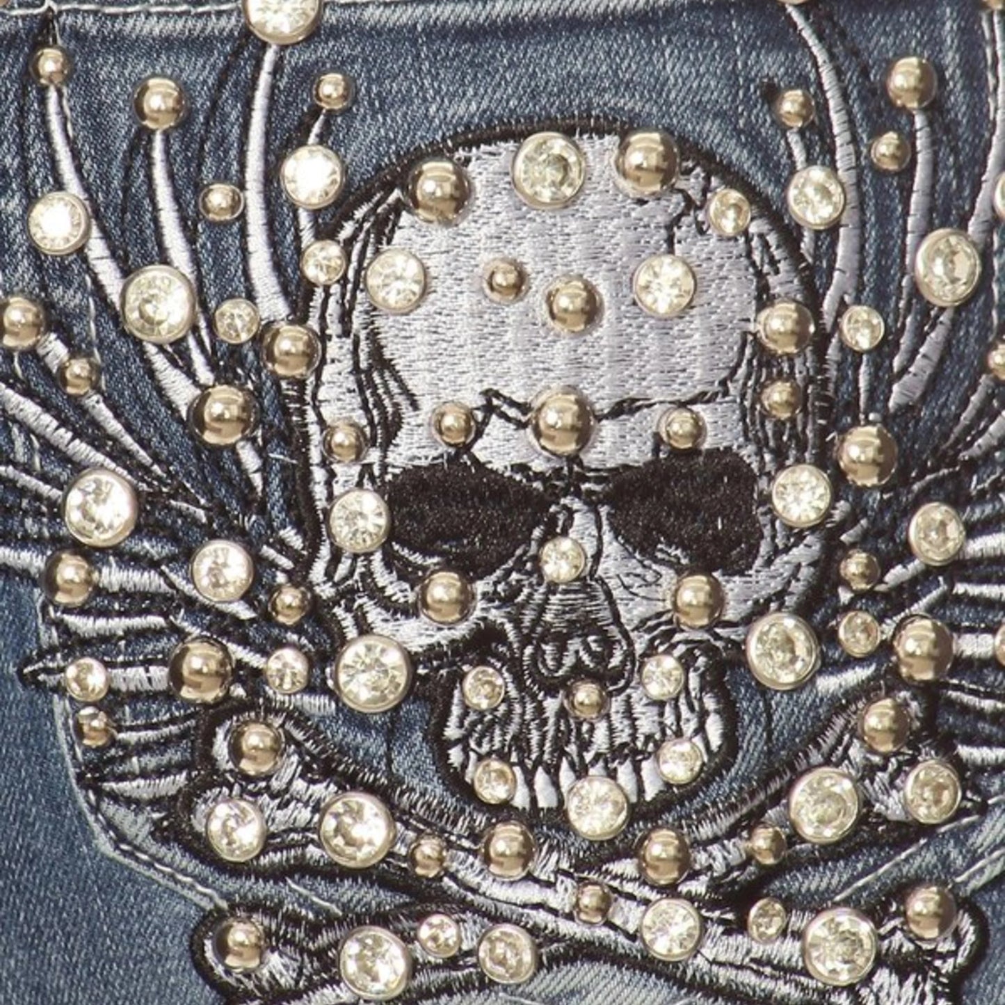Rhinestone skull-and-bones embroidery on back jean pocket with gold-tone studs