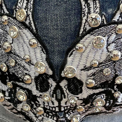 Rhinestone skull wing embroidery detail on denim shorts pocket