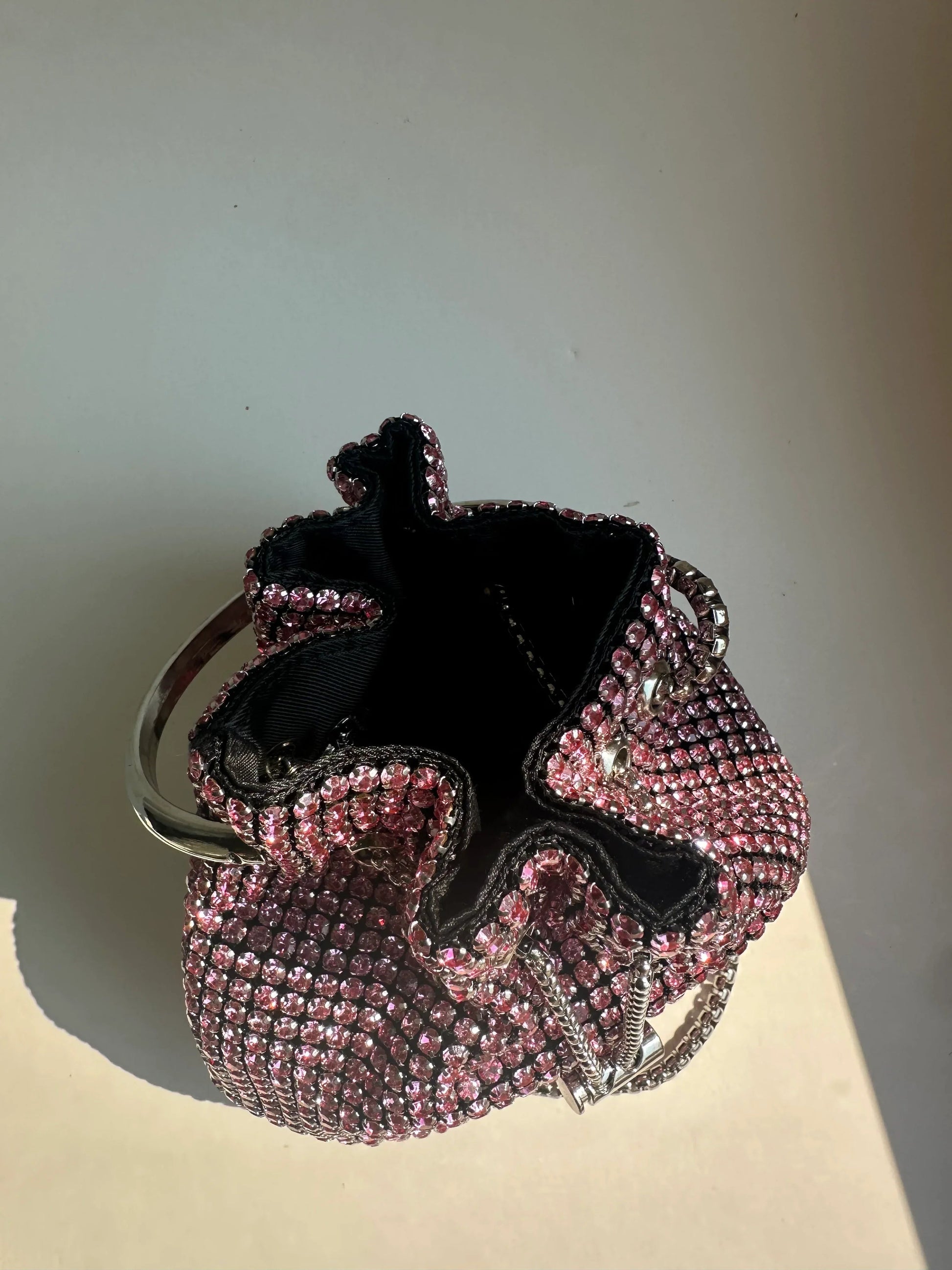 Pink rhinestone bucket bag open to show black fabric lining