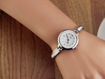 Silver watch bracelet on wrist with round white dial and metal link strap