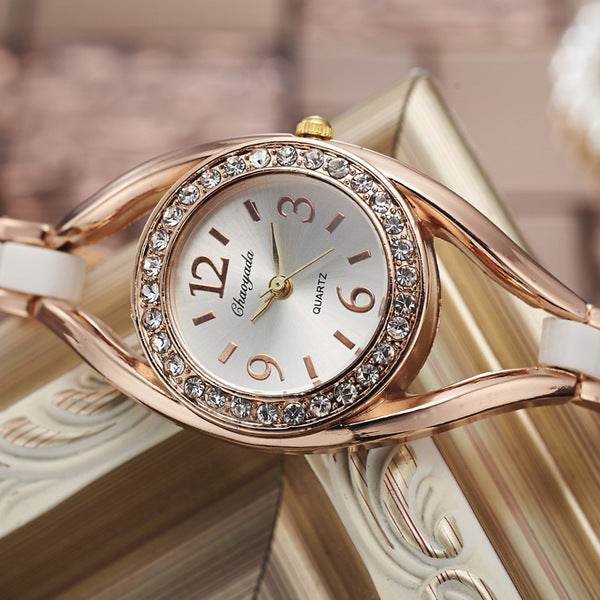 Rose-gold diamond bezel bracelet watch with white strap and round dial with gold hands