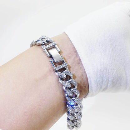 Silver diamond Cuban link bracelet with rectangular clasp on wrist.