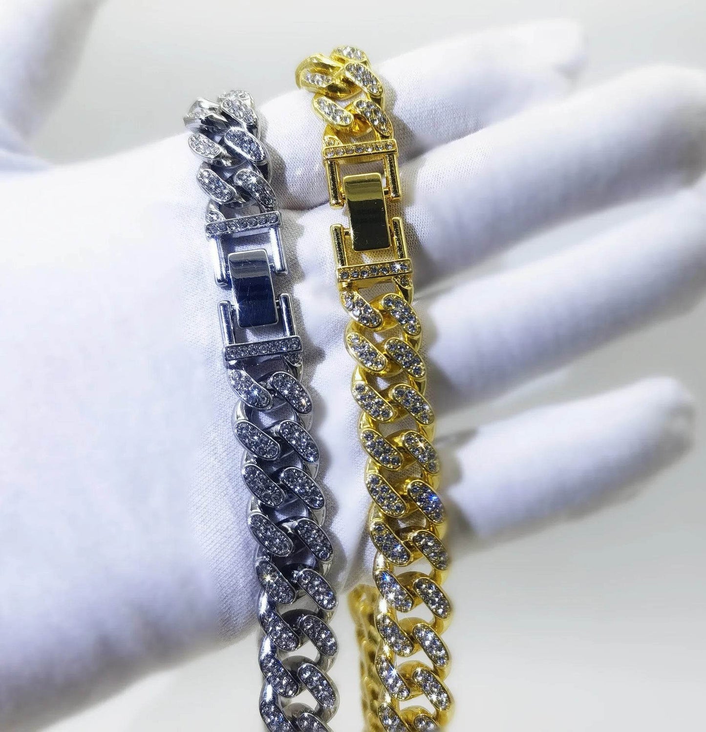Two diamond Cuban link bracelets, one gold and one silver, with clasp detail.
