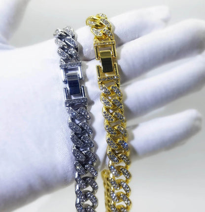 Two diamond Cuban link bracelets, one gold and one silver, with clasp detail.