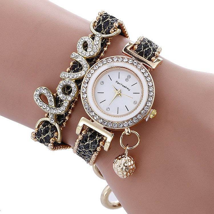Rhinestone bracelet watch with round white dial, gold-tone bezel, and black woven strap