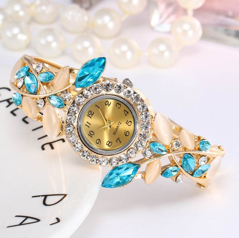 Gold-tone ladies bracelet watch with blue teardrop stones and crystal bezel round dial
