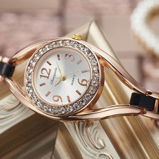 Rose-gold diamond bezel bracelet watch with black strap and round white dial
