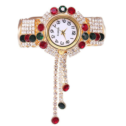 Gold-tone rhinestone bracelet watch with red, black, and clear stones; round quartz dial