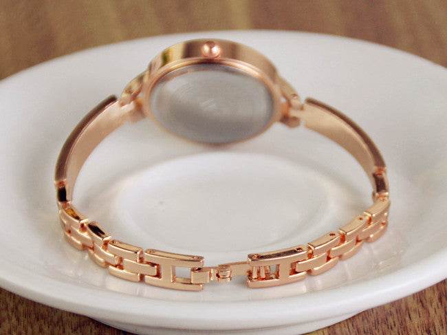Rose gold watch bracelet with linked band and round bezel on a white display