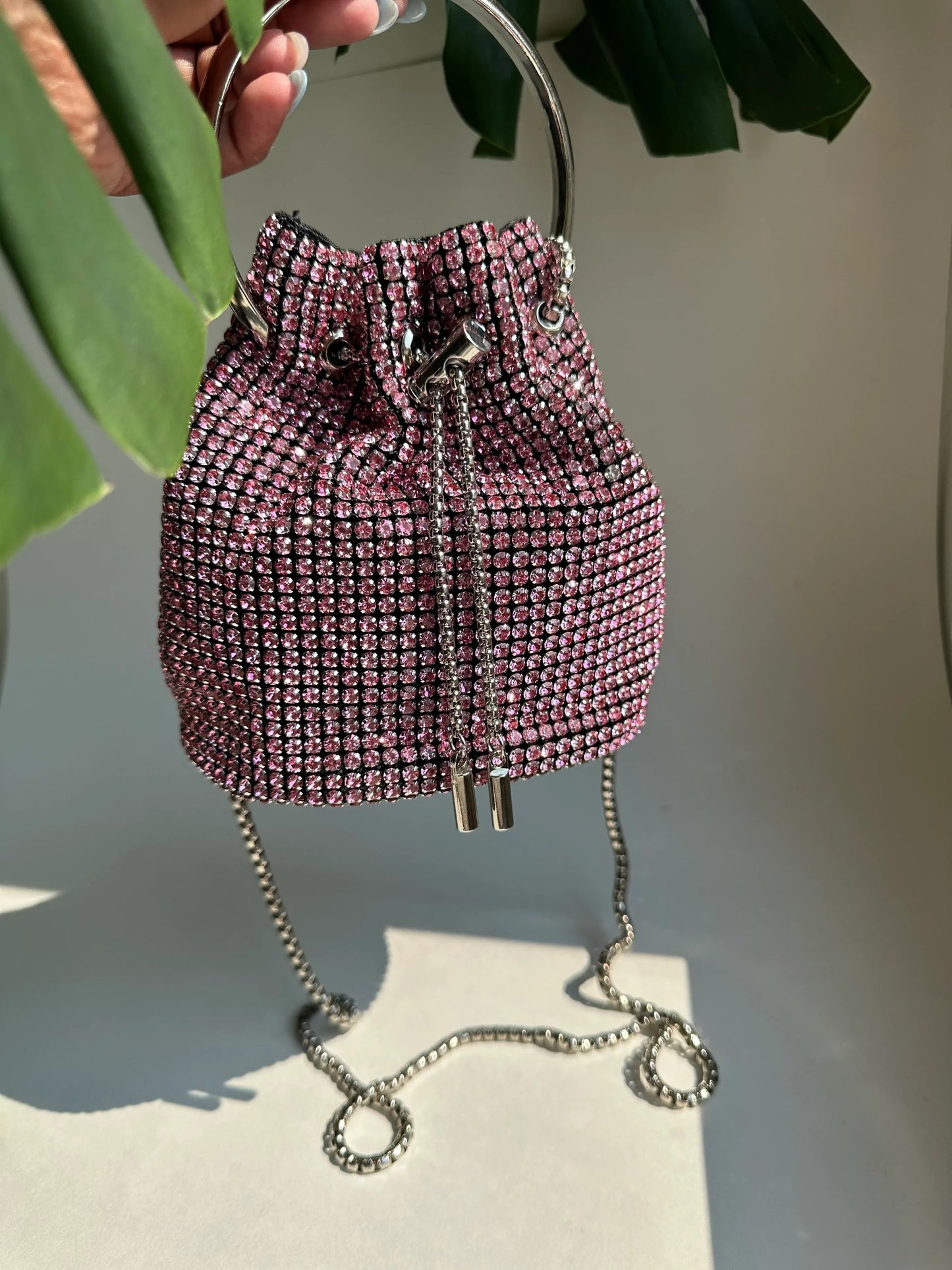 Pink rhinestone bucket bag with drawstring closure and crossbody chain strap