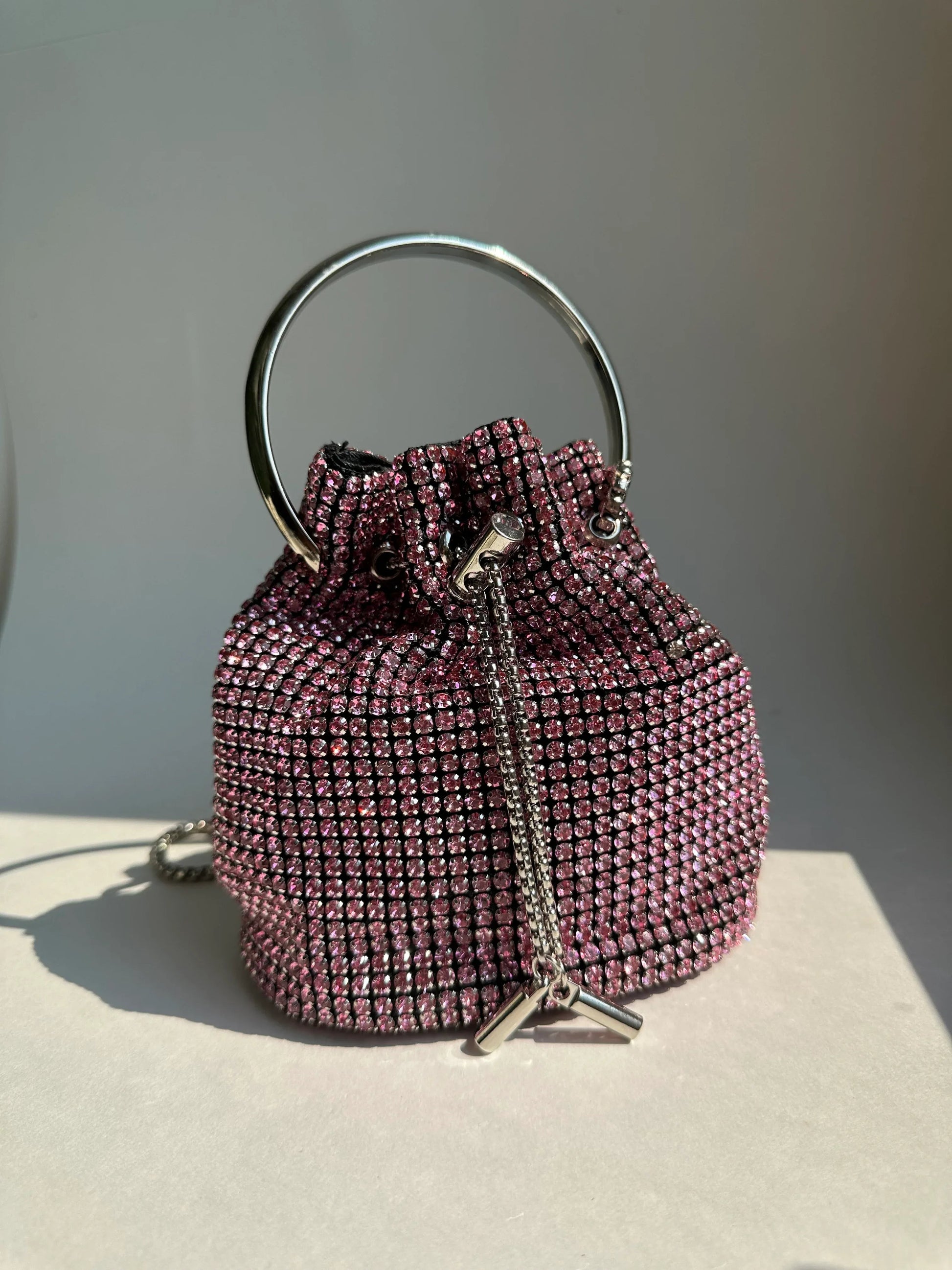 Pink rhinestone bucket bag with circular top handle and drawstring closure