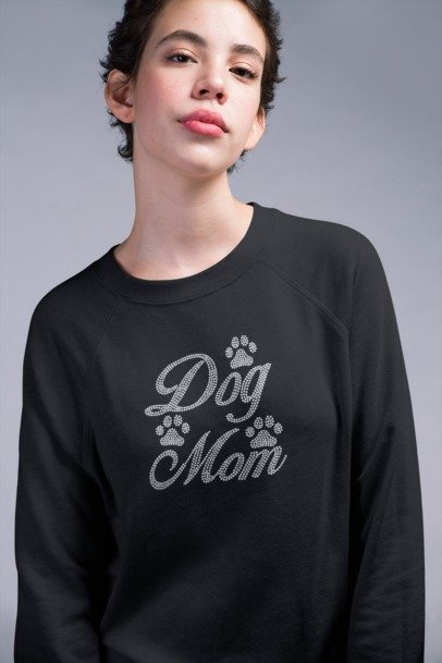 Person wearing a black sweatshirt with 'Dog Mom' text and paw prints on a gray background