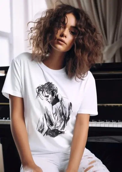 A woman with curly brown hair wearing a white graphic t-shirt with a black ink sketch of a person, posed in front of a piano.