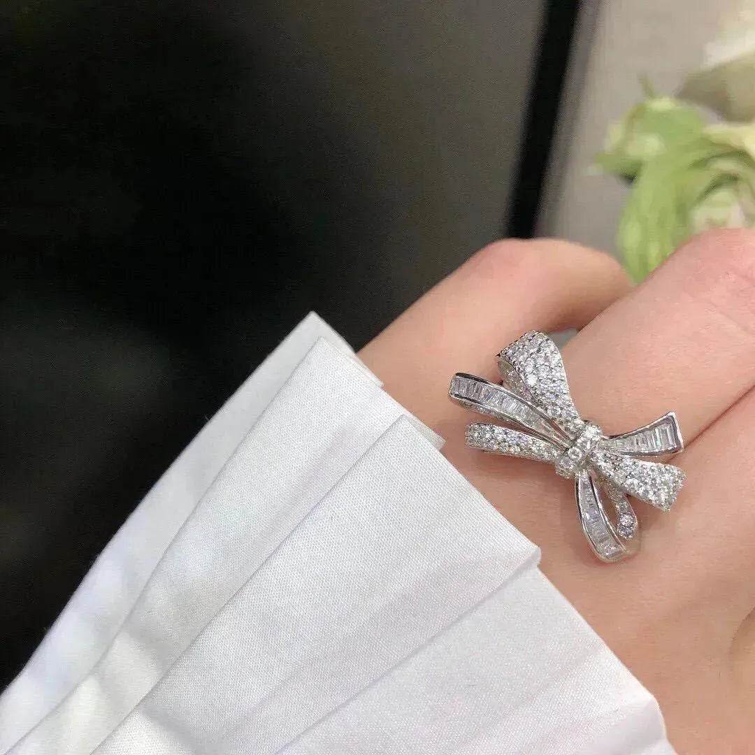 Silver-tone diamond bow ring on palm, open ribbon bow with prong-set stones