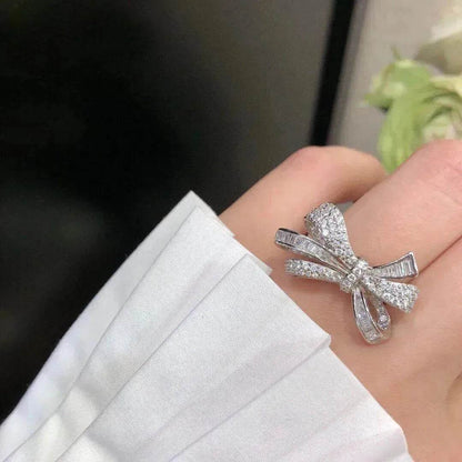 Silver-tone diamond bow ring on palm, open ribbon bow with prong-set stones