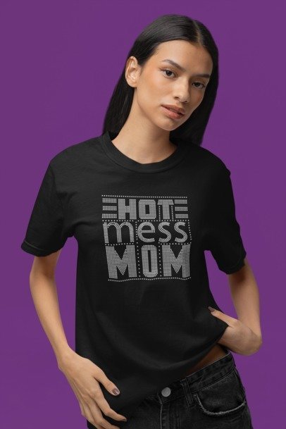 Woman wearing a black t-shirt with 'Hot Mess Mom' text on a purple background