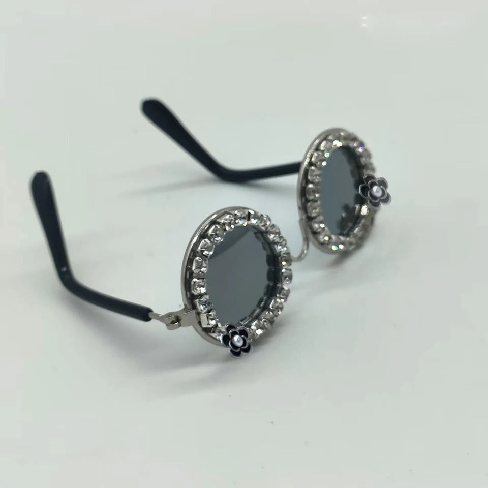 Rhinestone pet sunglasses with oval black lenses, curled arms, and flower charms