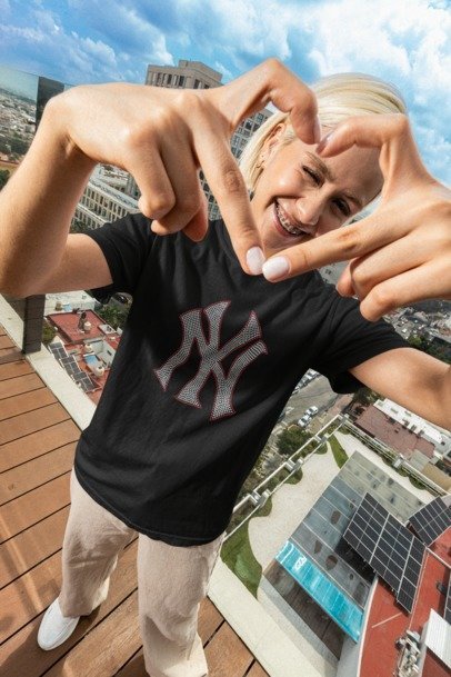 Person making a heart shape with their hands on a rooftop with cityscape in the background