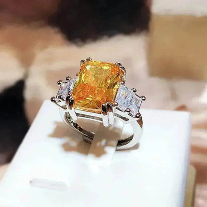 Orange-yellow square-cut crystal ring with silver band and rhinestone accents