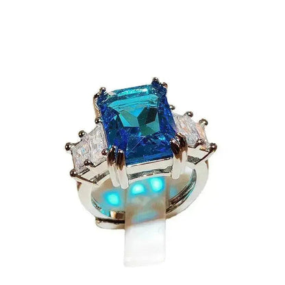 Teal-blue square-cut crystal ring with silver band and side rhinestones