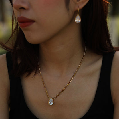 Gold-tone link chain necklace with teardrop crystal pendant on neckline.