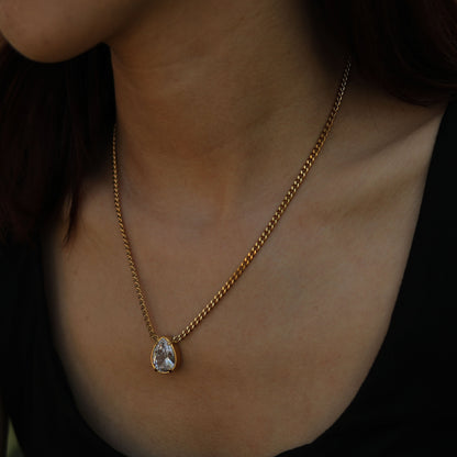 Gold-tone link chain necklace with oval teardrop crystal pendant, bezel setting.