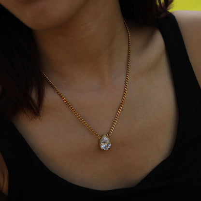 Gold-tone link chain necklace with small teardrop crystal pendant.