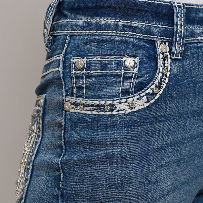 Close-up of women’s blue jeans front pocket with silver-toned studs and chain embroidery