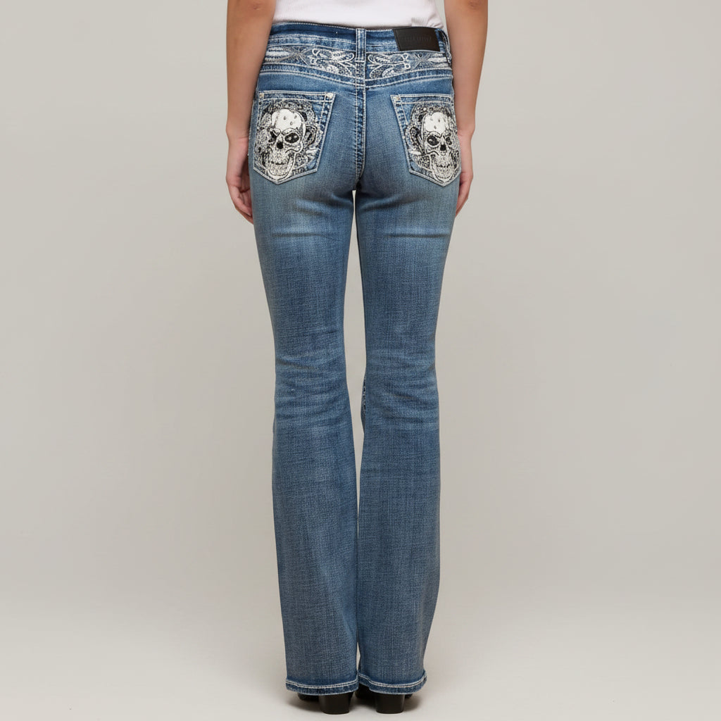 Blue jeans with skull designs on pockets against a plain background