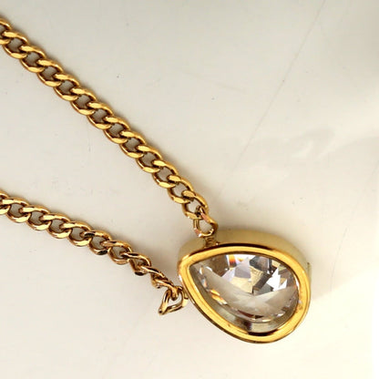 Close-up of gold-tone link chain with teardrop crystal pendant bezel.