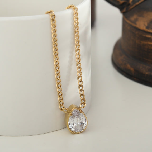 Gold-tone link chain necklace with teardrop crystal pendant, side view.