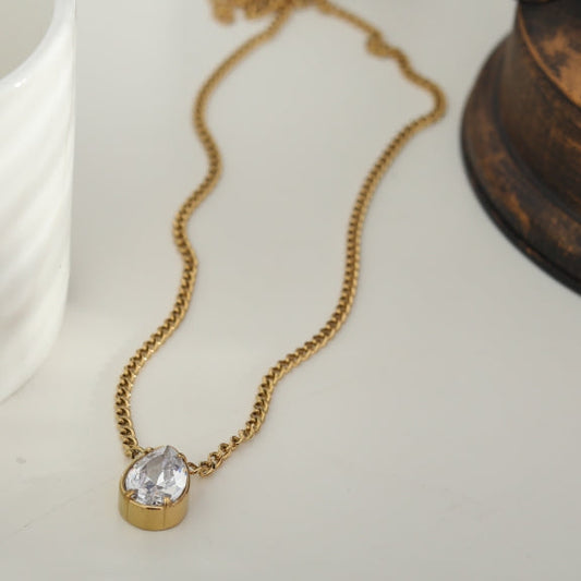 Gold-tone chain necklace with large teardrop crystal pendant in round bezel.