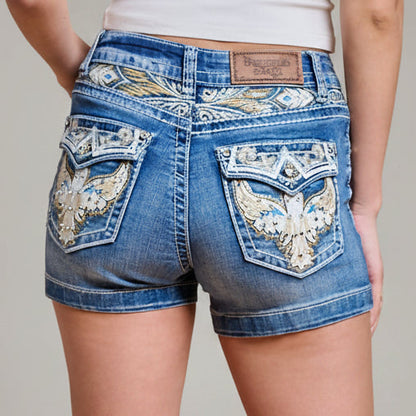 Blue denim high-waisted shorts with embroidered eagle pocket panels and back tag.